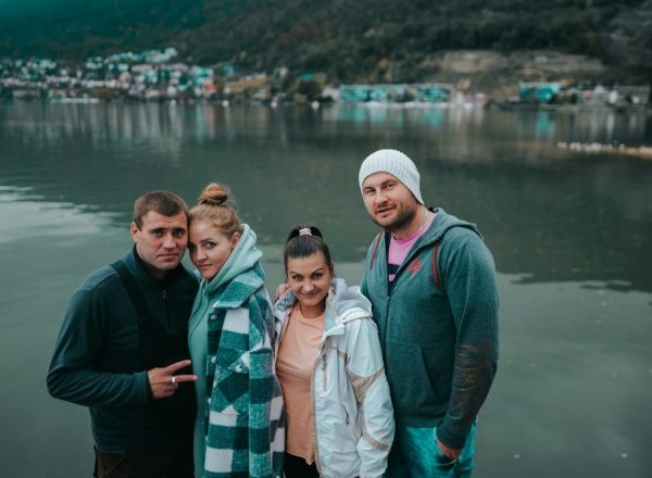 a group of people posing for a photo in front of a body of water